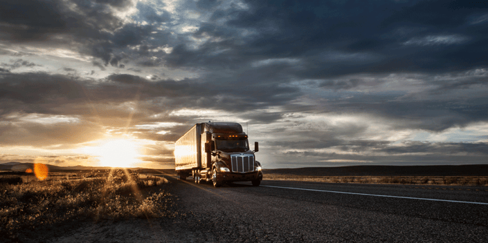 Truck driving on rural road at sunset