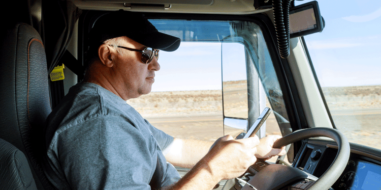 Truck driver looking at cell phone while driving