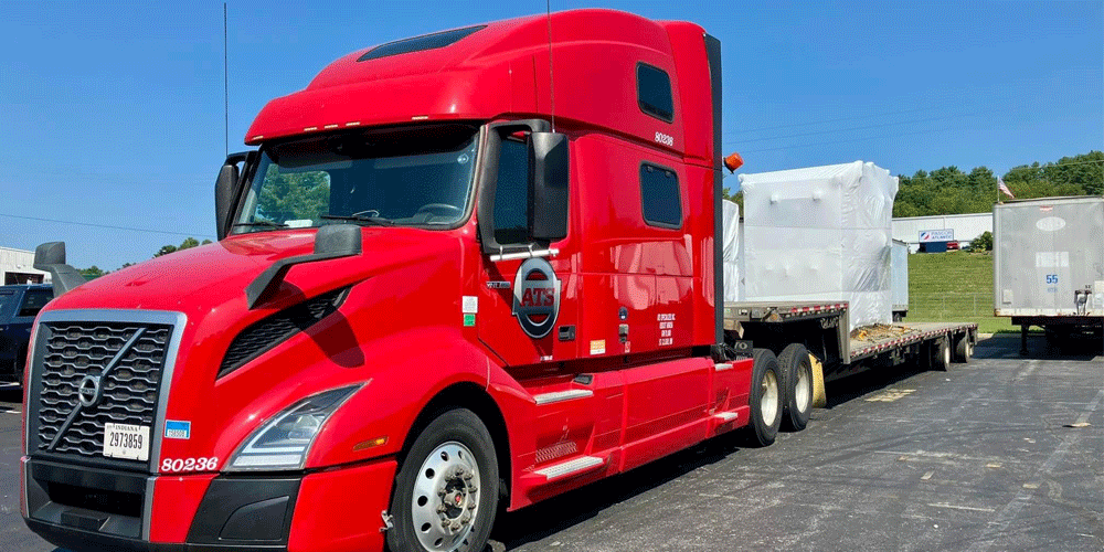 Red ATS truck hauling a white tarped load.