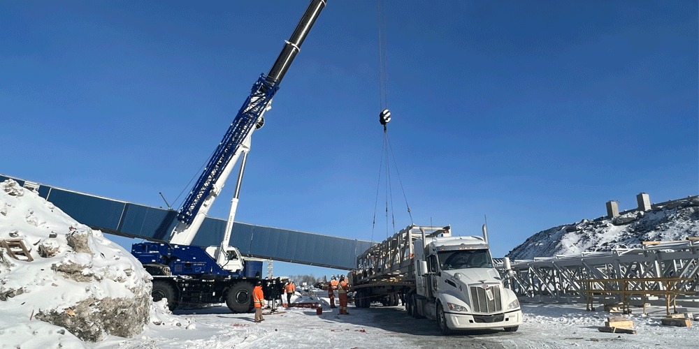 Crane loading semi-truck in a snowy area.