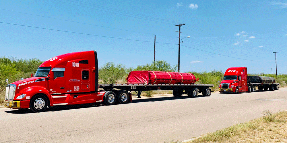 two red semi trucks with flatbed loads