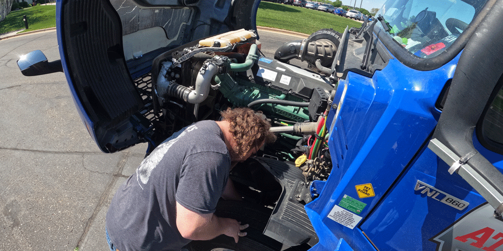 Man inspecting under the hood of his semi.