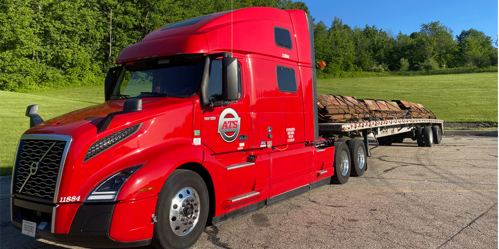 Red ATS truck with flatbed trailer.