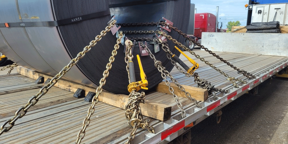 Angled view of a coil secured to a flatbed trailer.