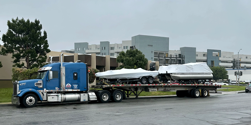 Two boats secured on a flatbed trailer.