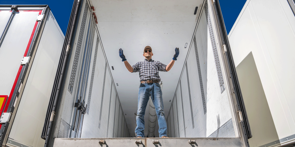 Empty dry van trailer with man standing inside.