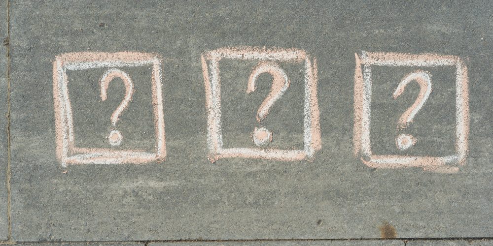 Three question marks written in chalk.