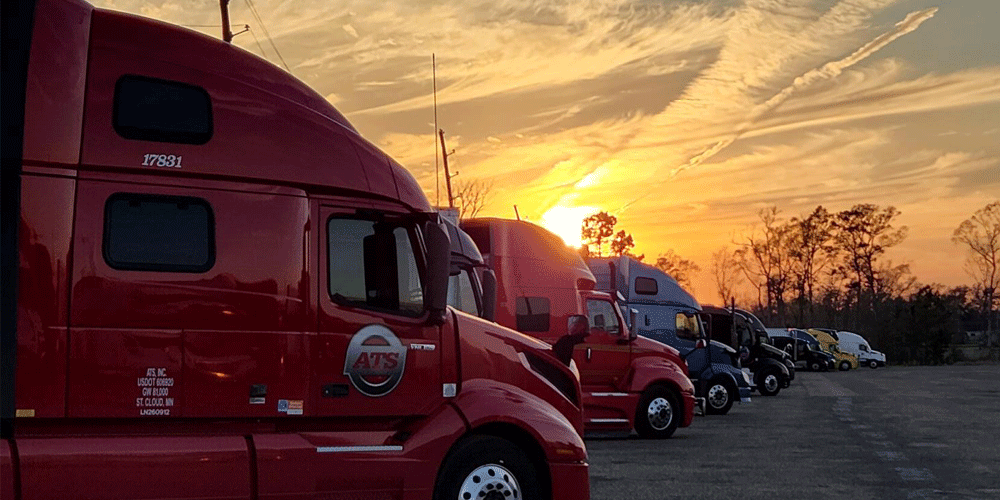 ATS semi-trucks parked in a lot at sunset