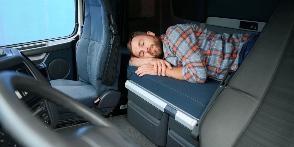 Man sleeping in sleeper berth of semi-truck.