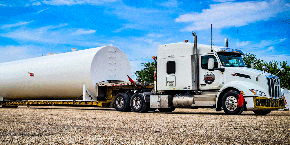 White ATS semi-truck hauling a large oversized tank.