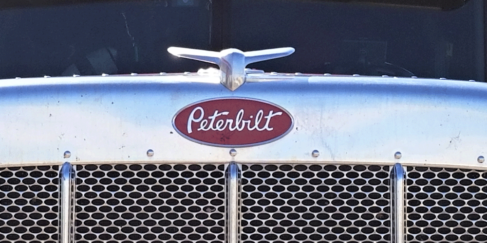 Zoomed in hood of a semi-truck with the Peterbilt logo