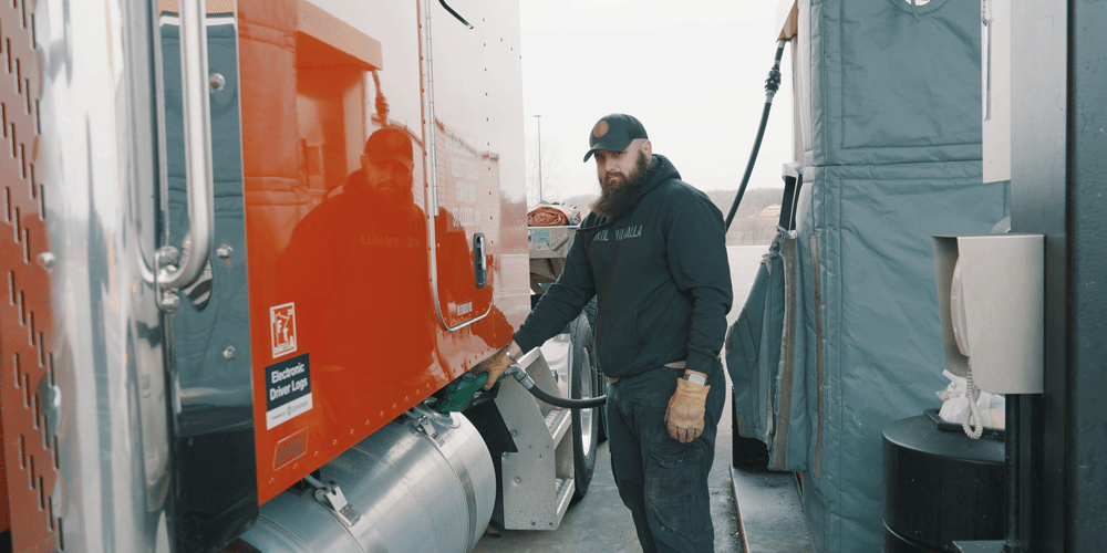 Truck driver fueling up semi-truck.