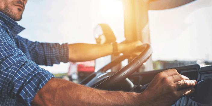 Man in the driver's seat of a semi-truck. He's adjusting controls.