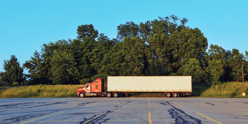 A dry van truck sits in an abandoned parking lot
