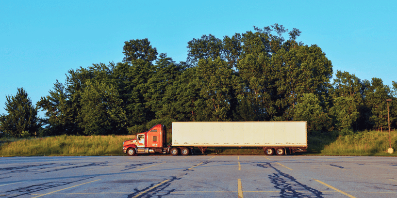 A dry van truck sits in an abandoned parking lot