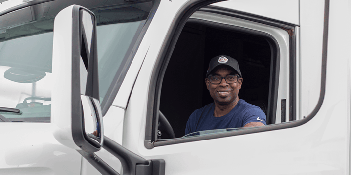 ATS driver smiles from inside the cab of a semi. The best heavy haul trucking companies in 2026.