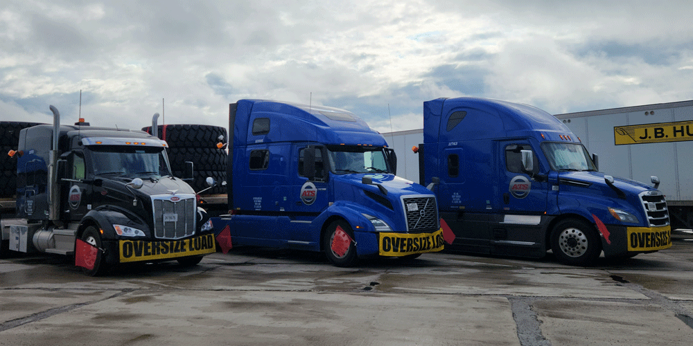 Three ATS trucks parked in front of a J.B. Hunt facility.