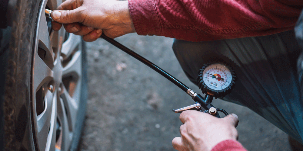 Man putting tire gauge on one of his truck's tires.