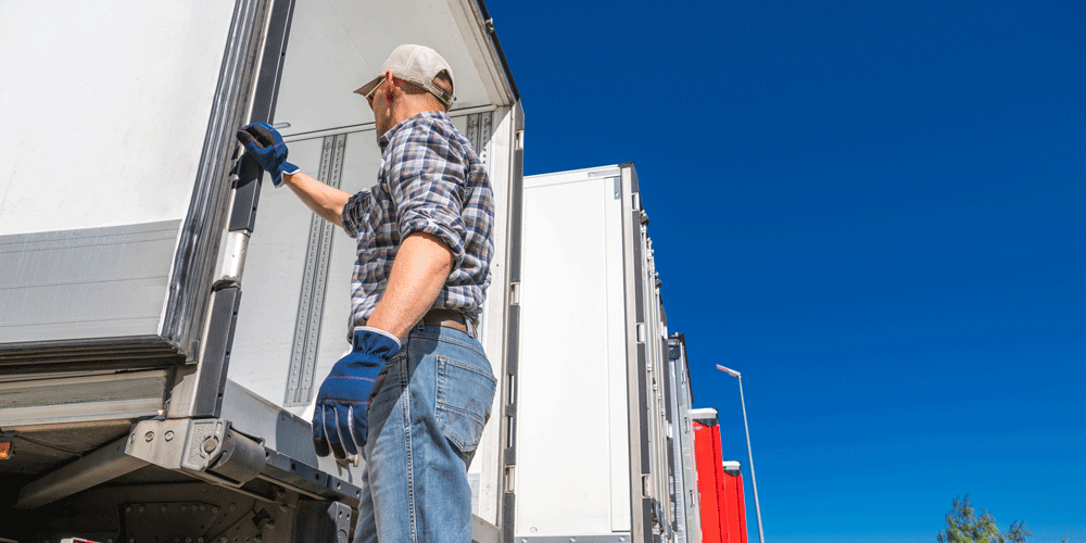 Truck driver closing the doors of a van trailer. 