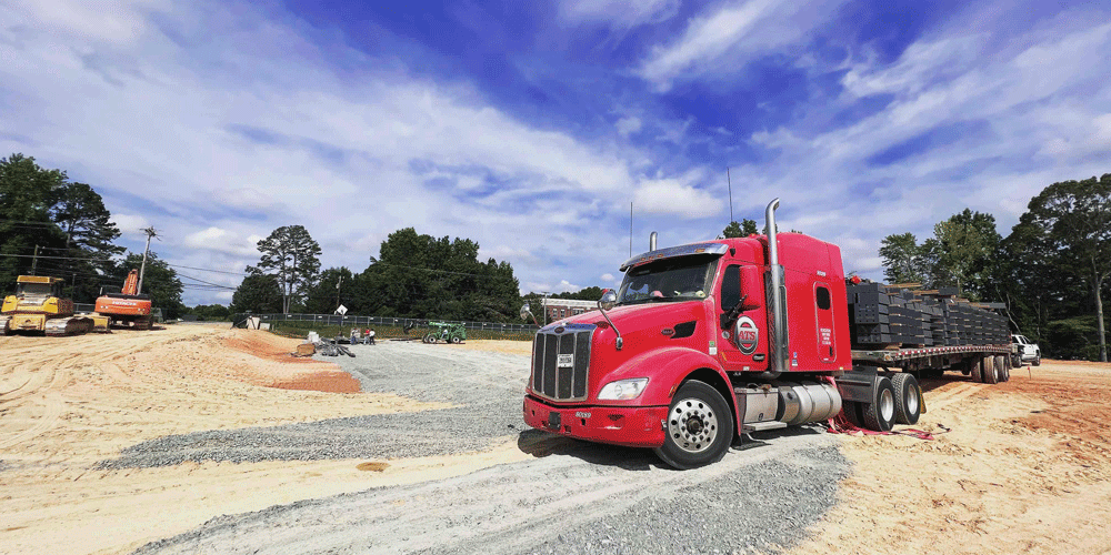 Side view of a red semi with a flatbed trailer.