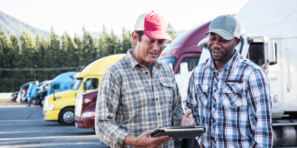 Two men talking to each other in front of a line of parked semis.