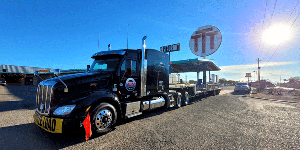 Black ATS flatbed truck parked at truck stop with sun shining