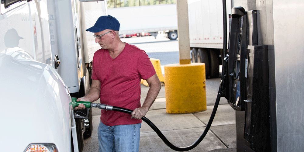 Man in read shirt and hat fueling his white semi.