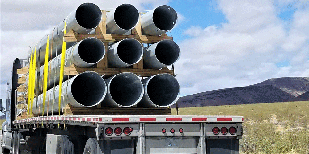 Semi-truck hauling pipes in the mountains.