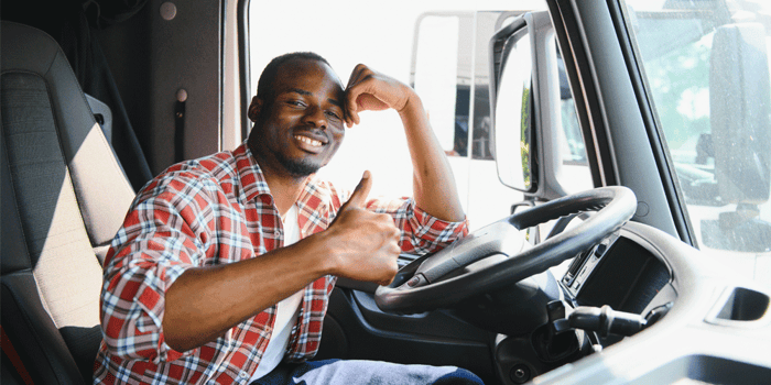Truck driver giving thumbs up from inside cab; TWIC card guide and benefits for drivers; ATS