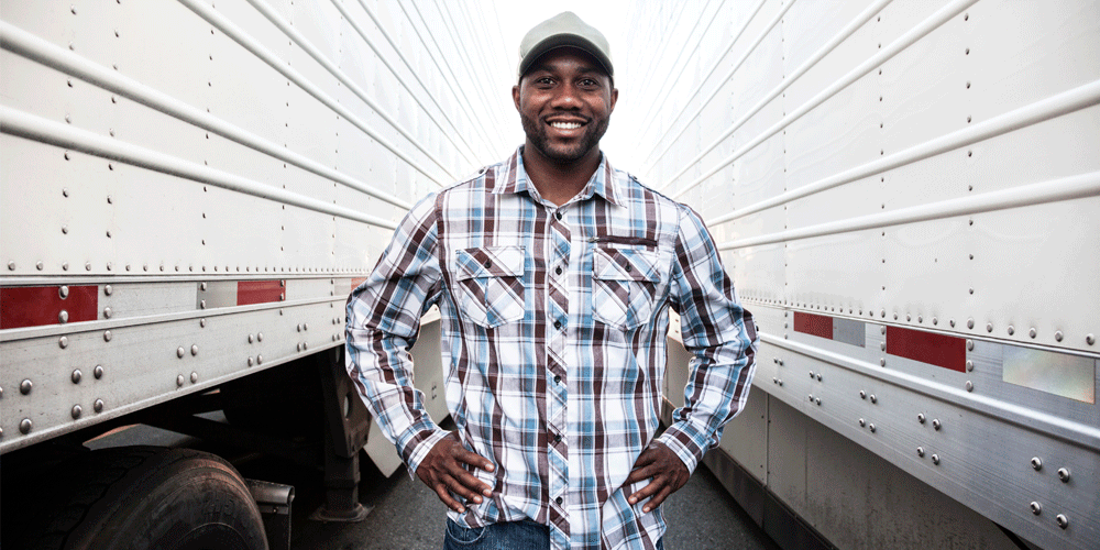 A man standing between two van trailers smiling.