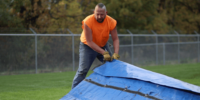 Truck driver unrolling flatbed tarps