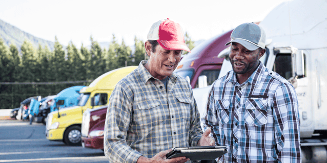 Driver manager and driver looking at a tablet together in a truck parking lot, CDL citations vs. warnings, Anderson Trucking Service