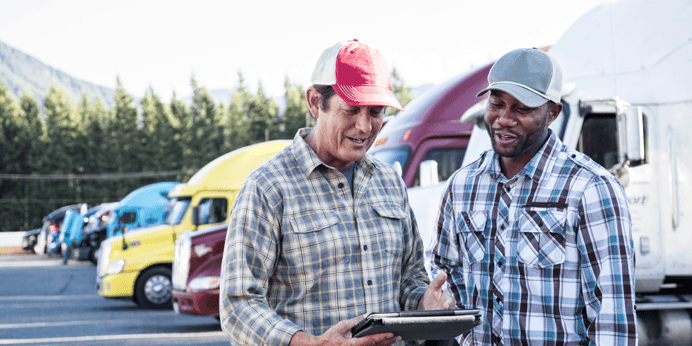 Driver manager and driver looking at tablet together in truck parking lot