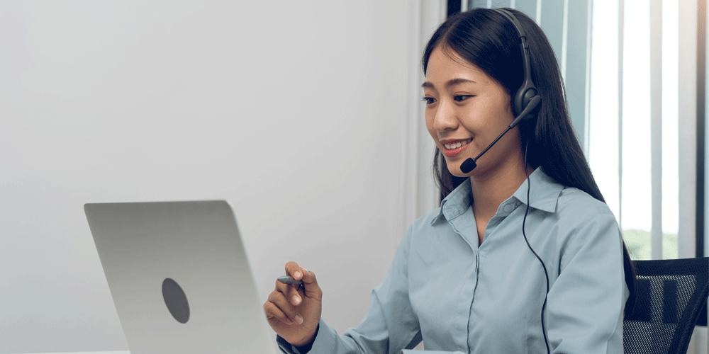 Woman talking on a headset. A laptop is in front of her.
