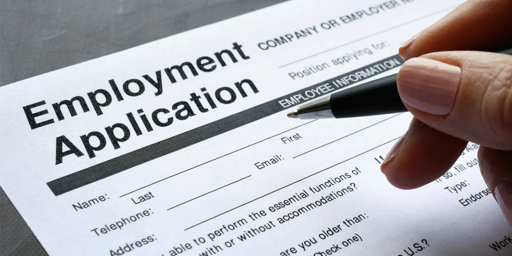 A close up view of an employment application. A hand can be seen hovering over the paper with a pen.
