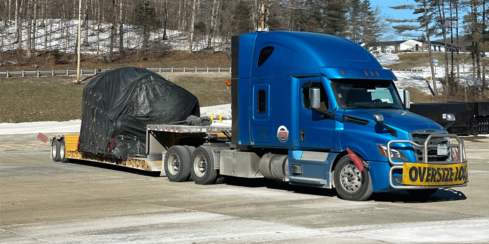 Blue ATS truck hauling a black tarped load.