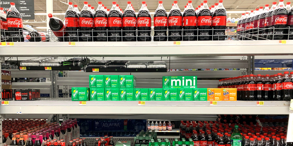 Shelves at a grocery store filled with soda bottles and cans.