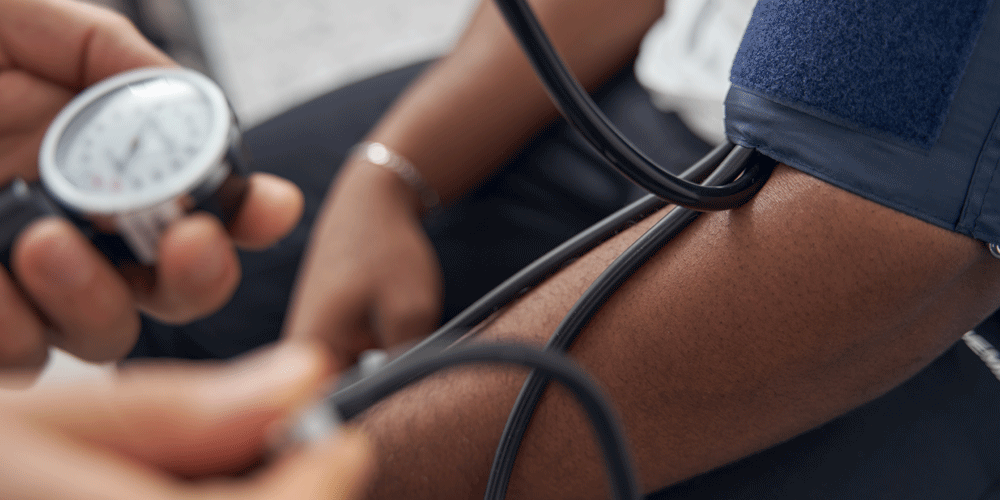 Close-up view of a man getting his blood pressure taken with an arm cuff.