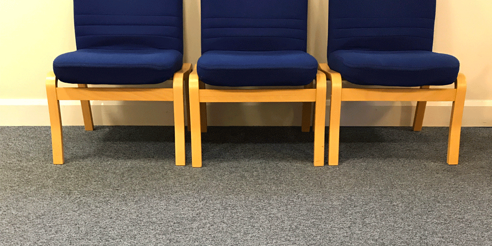 Three empty blue waiting room chairs.