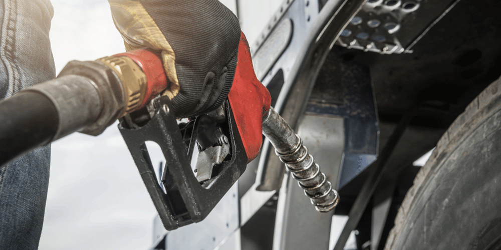 Holding a fuel pump nozzle with gloved hands.