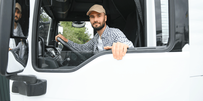 Truck driver sitting in his semi-truck with the window down; semi-truck passenger policy; ATS; Anderson Trucking Service