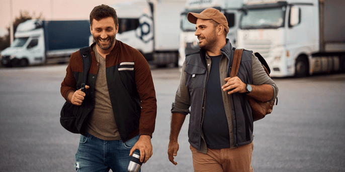 Two truck drivers walking through a truck parking lot; semi-truck passenger policies; semi-truck rider rules; Anderson Trucking Service; ATS