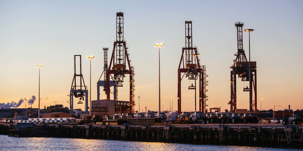 Cargo cranes at a port at dusk.