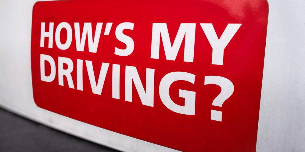 "How's My Driving?" written in white letters on a red box on the side of a white truck.