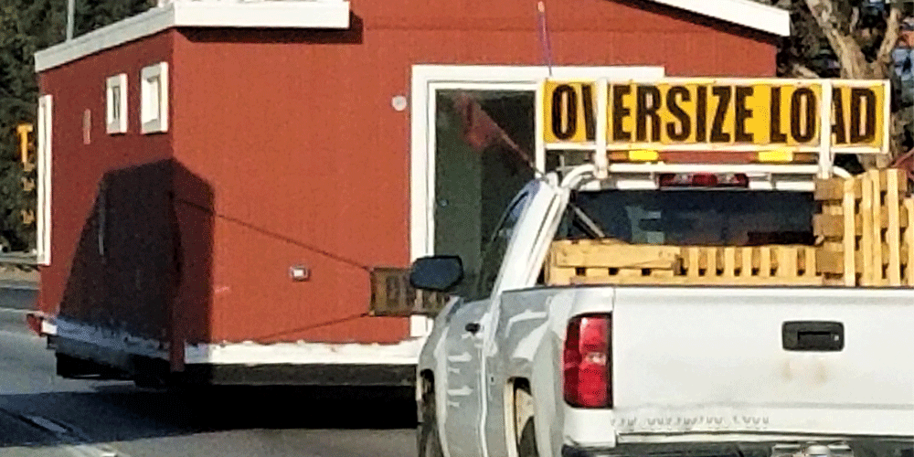 Pilot car following an oversized load (a house on a semi-truck). 