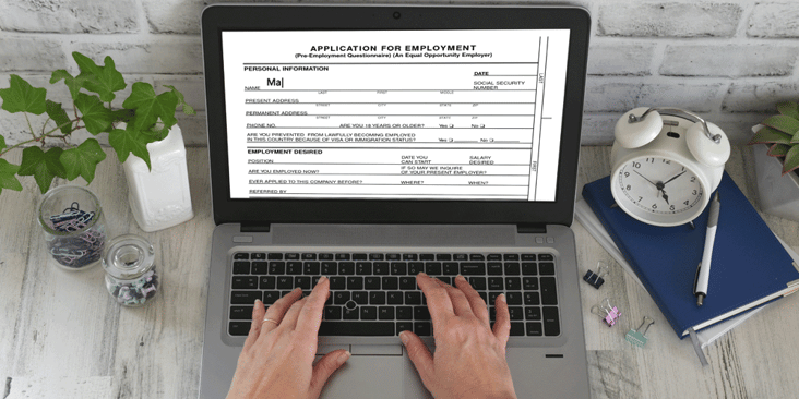 Person sitting at desk and filling out an online job application on their laptop. SF-86 security clearance. DOD trucking