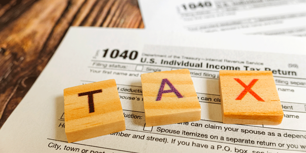 Word blocks spelling TAX lying on a 1040 Tax Form.