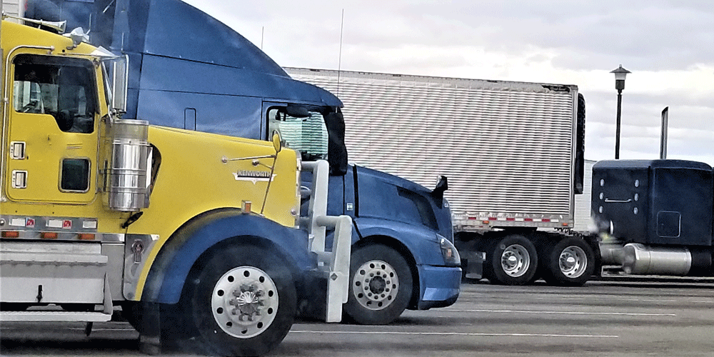 A blue truck and a yellow truck parked side-by-side.