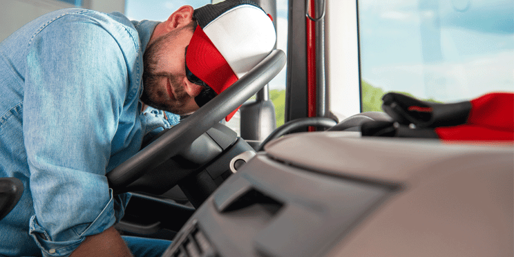 Exhausted truck driver sleeping on the steering wheel of his semi-truck; ATS; how does the split sleeper berth rule work