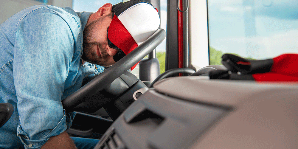 Exhausted truck driver sleeping on the steering wheel.